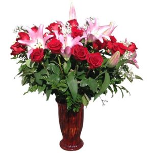 Vase with red roses, lilies and green plants