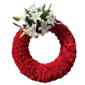 Sympathy arrangement with red carnations and white lilies in a circle